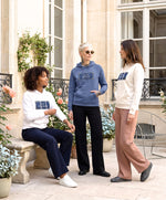Trois femmes portant des hoodies Salut Fred blanc, écru et bleu ardoise de la collection Rues de France dans une cour parisienne lumineuse