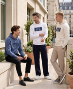 Trois hommes portant des hoodies Salut Fred bleu ardoise, blanc et écru de la collection Rues de France dans une rue parisienne ensoleillée