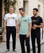 Groupe d’hommes portant des t-shirts classiques Salut Fred de la collection Pride « This is not woke. You are just a dick. » en blanc, bleu opalin et noir, avec slogans multicolores imprimés au centre de la poitrine dans une rue parisienne élégante