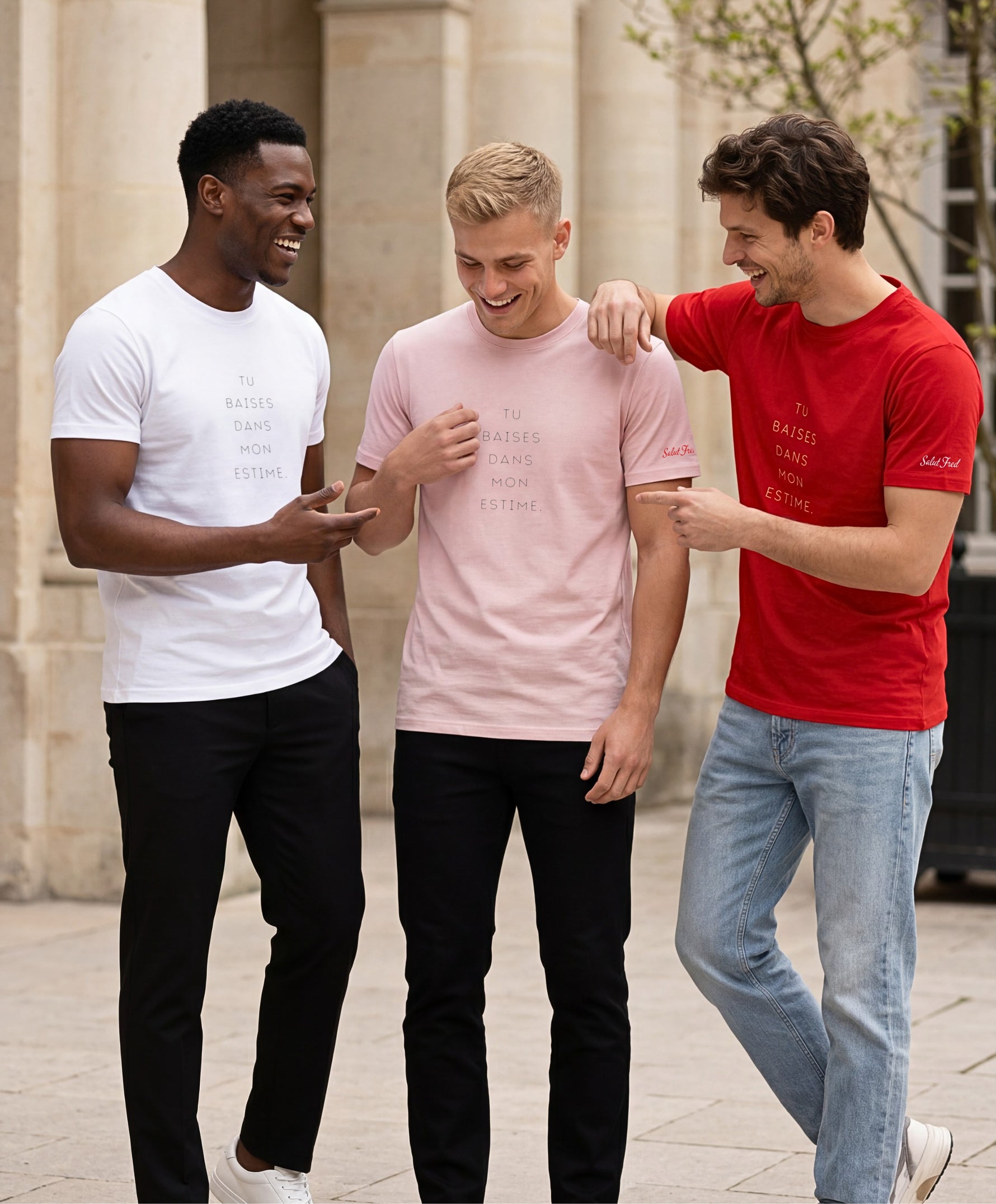 Trois hommes portant des t-shirts classiques Salut Fred blanc, rose poudré et rouge avec slogan « Tu baises dans mon estime » dans une cour parisienne lumineuse