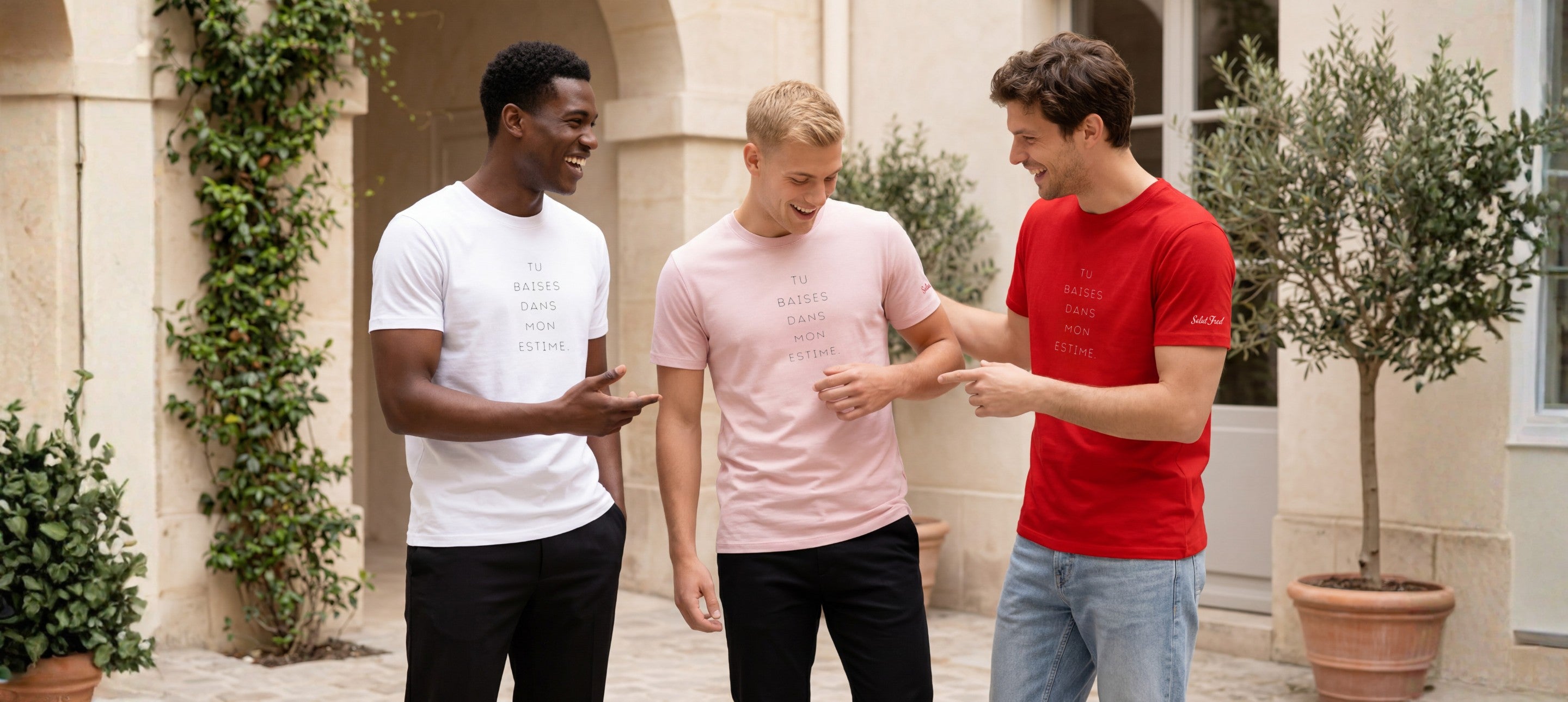 Ligne de t-shirts classiques « Tu baises dans mon estime. » en blanc, rose poudré et rouge, portés par trois hommes dans une cour parisienne élégante.