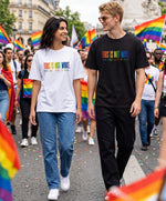 Un homme portant un t-shirt oversize noir et une femme portant un t-shirt oversize blanc Salut Fred de la collection « This is not woke. You are just a dick. » lors d’une marche Pride, avec slogan multicolore imprimé au centre de la poitrine et logo Salut Fred arc-en-ciel sur la manche gauche