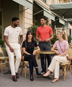 Gamme de t-shirts classiques monogramme SF Salut Fred portée par des hommes et femmes dans les coloris écru, noir, orange coquelicot et rose poudré, assis et debout en terrasse de café parisienne