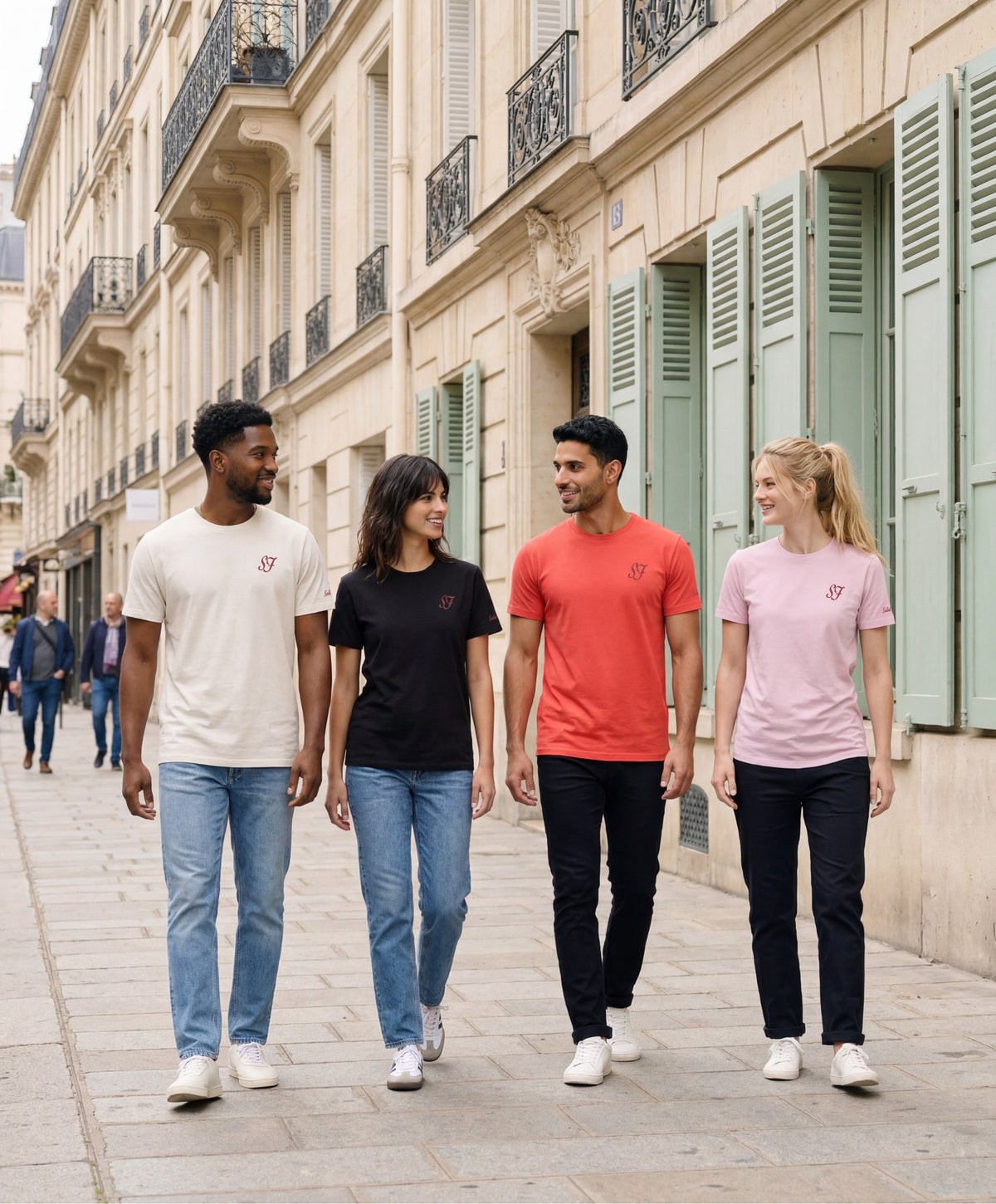 Gamme de t-shirts classiques monogramme SF Salut Fred portée par des hommes et femmes dans les coloris écru, noir, orange coquelicot et rose poudré, marchant dans une rue parisienne