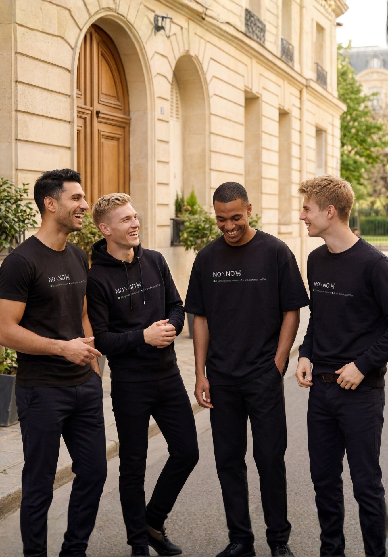 Ligne « No pic No Chat(te) » en noir comprenant t-shirt classique, t-shirt oversize, sweatshirt et hoodie, portés par quatre hommes dans une rue résidentielle élégante.