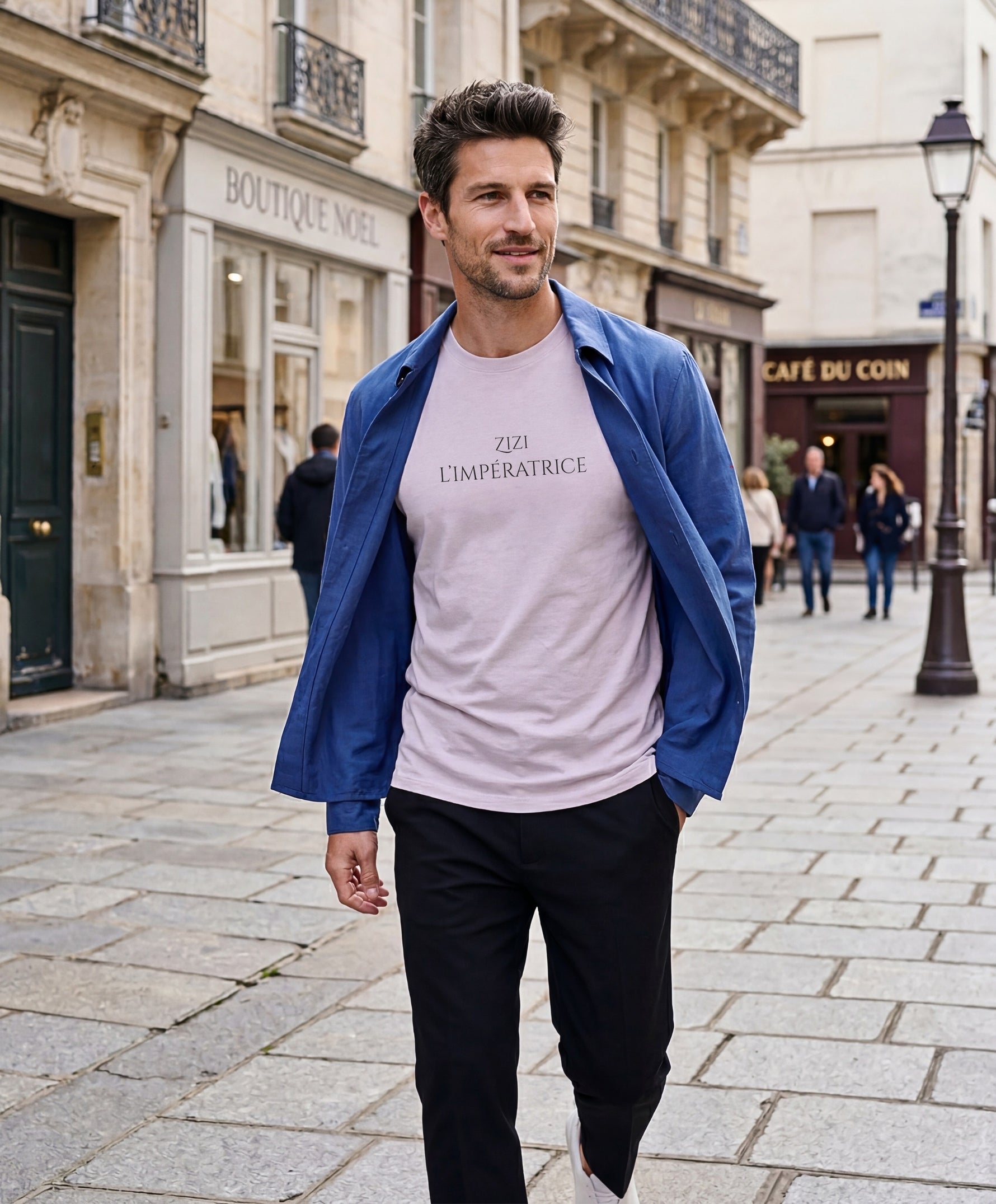 Vue de face d’un homme portant le t-shirt classique lilas « Zizi l’Impératrice » avec texte imprimé noir centré sur la poitrine et logo Salut Fred sur la manche gauche, dans une rue parisienne.