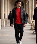 Vue de face d’un homme portant un t-shirt classique rouge Salut Fred avec slogan « Tu baises dans mon estime » sous une veste noire dans une galerie parisienne élégante