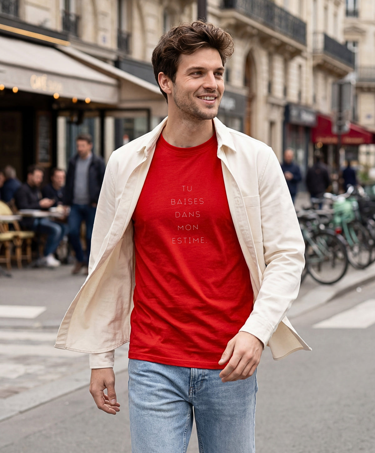 Vue de face d’un homme portant un t-shirt classique rouge Salut Fred avec slogan « Tu baises dans mon estime » dans une rue parisienne animée