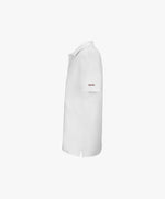 Vue côté gauche du polo blanc Salut Fred avec broderie « Thérap(e)ute. À votre service », avec Salut Fred brodé sur la manche gauche