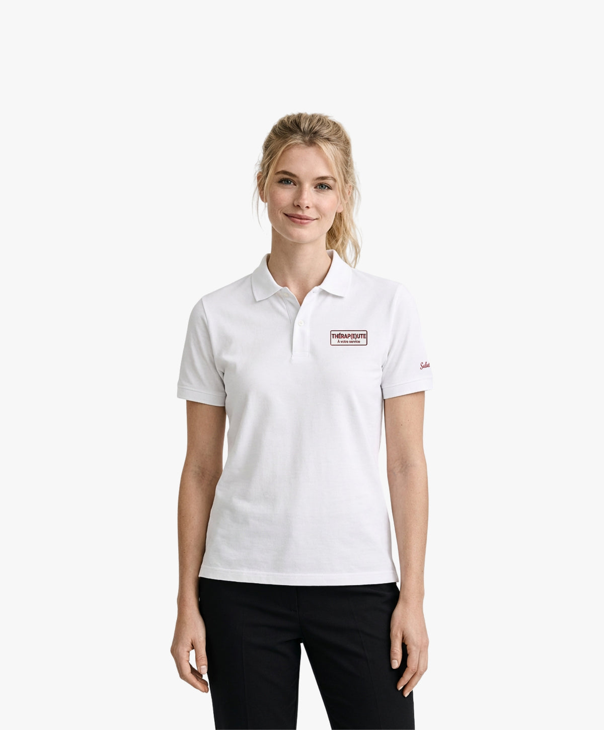 Vue de face d’une femme portant un polo blanc Salut Fred avec broderie « Thérap(e)ute. À votre service » sur la poitrine et Salut Fred brodé sur la manche gauche dans une rue parisienne élégante