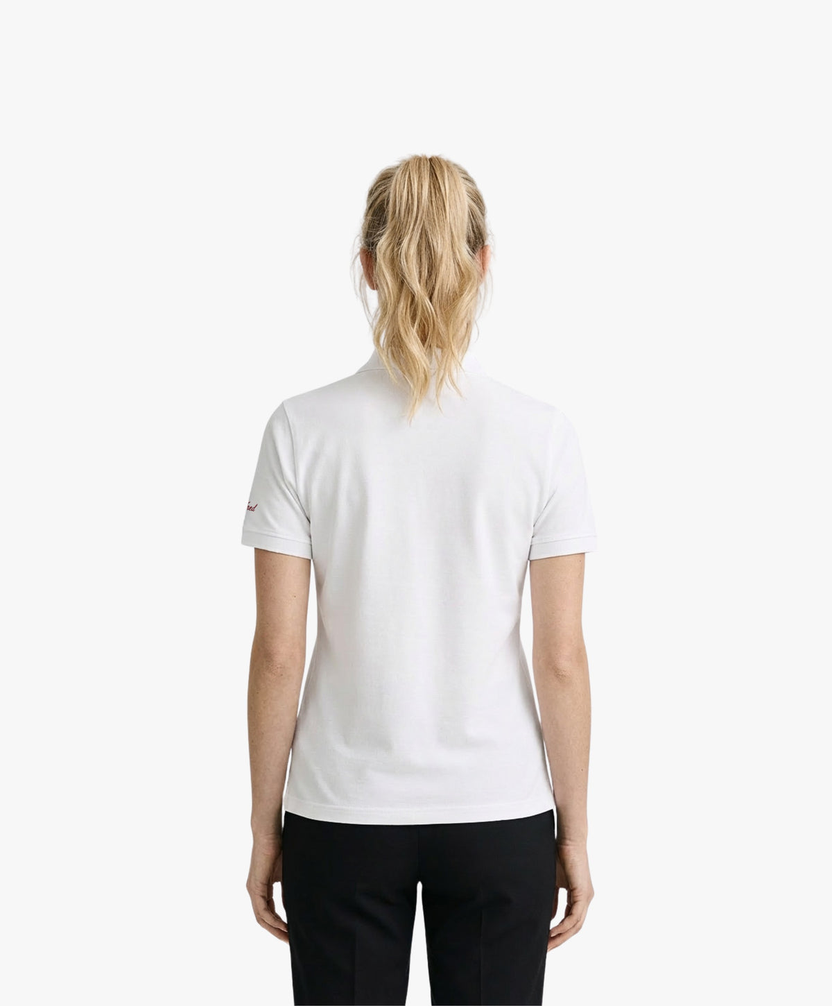 Vue de dos d’une femme portant un polo blanc Salut Fred dans une rue parisienne élégante