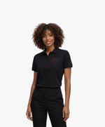 Vue de face d’une femme portant un polo noir Salut Fred avec broderie « Thérap(e)ute. À votre service »