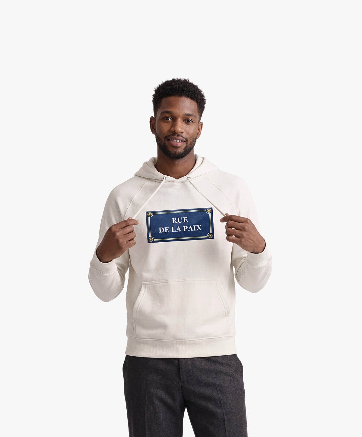 Vue de face d’un homme portant un hoodie écru Salut Fred avec motif Rue de la Paix de la collection Rues de France