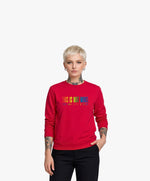 Vue de face d’une femme portant un sweatshirt rouge Salut Fred de la collection « This is not woke. You are just a dick. » avec slogan multicolore imprimé au centre de la poitrine