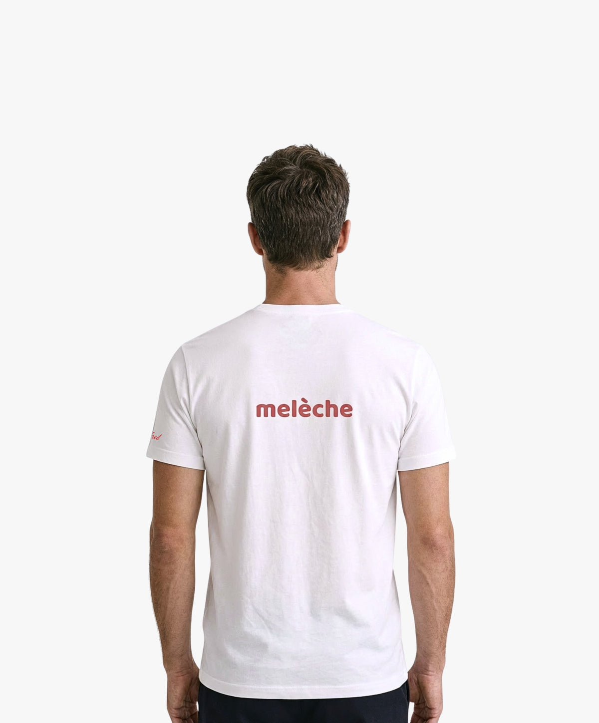 Vue de dos d’un homme portant un t-shirt classique blanc Salut Fred avec melèche imprimé au centre du dos dans une teinte melon pastel saumonée