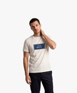 Vue de face d’un homme portant un t-shirt classique écru Salut Fred avec motif Quai Branly de la collection Rues de France