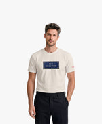Vue de face d’un homme portant un t-shirt classique écru Salut Fred avec motif Rue de la Paix de la collection Rues de France
