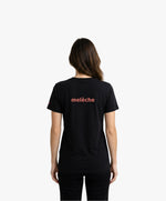 Vue de dos d’une femme portant un t-shirt classique noir Salut Fred avec melèche imprimé au centre du dos