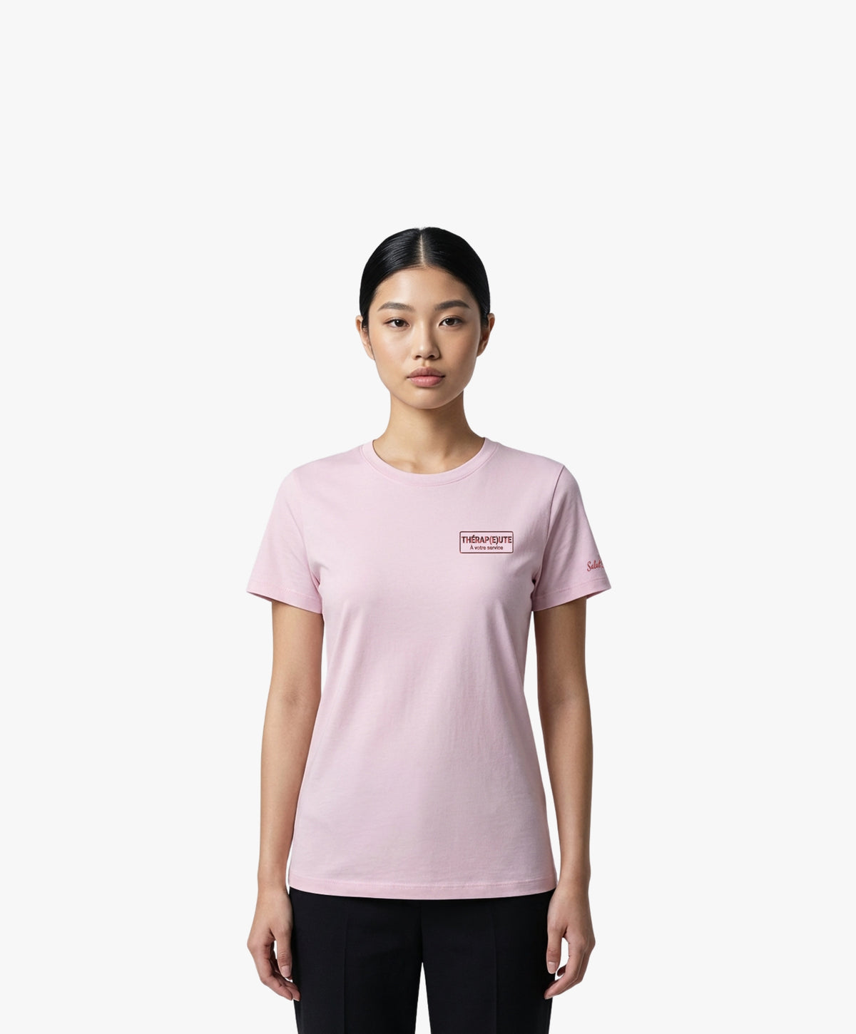 Vue de face d’une femme portant un t-shirt classique rose poudré Salut Fred avec broderie « Thérap(e)ute À votre service » sur la poitrine gauche