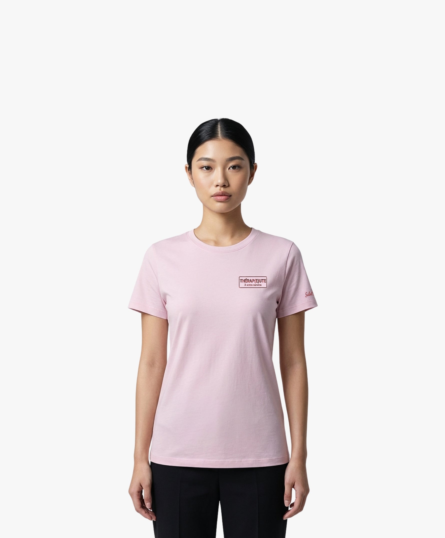 Vue de face d’une femme portant un t-shirt classique rose poudré Salut Fred avec broderie « Thérap(e)ute À votre service » sur la poitrine gauche