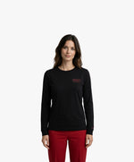 Vue de face d’une femme portant un t-shirt manches longues noir Salut Fred avec motif brodé « Thérap(e)ute. À votre service » sur la poitrine gauche