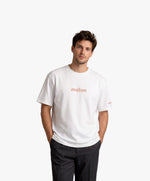 Homme vue de face portant le t-shirt oversize blanc « Melon Melèche » avec texte imprimé « melon » centré sur la poitrine et logo Salut Fred sur la manche gauche.