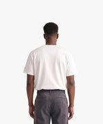 Vue de dos d’un homme portant un t-shirt oversize blanc Salut Fred avec motif Rue Duquesne de la collection Rues de France