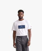 Vue de face d’un homme portant un t-shirt oversize blanc Salut Fred avec motif Rue Duquesne de la collection Rues de France