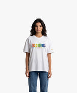 Vue de face d’une femme portant un t-shirt oversize blanc Salut Fred de la collection « This is not woke. You are just a dick. » avec slogan multicolore imprimé au centre de la poitrine et logo Salut Fred arc-en-ciel sur la manche gauche
