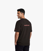 Homme vue de dos portant le t-shirt oversize noir « Melon Melèche » avec texte imprimé « melèche » centré dans le dos.