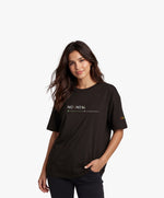 Vue de face d’une femme portant un t-shirt oversize noir Salut Fred avec motif « No pic No Chat(te) », où « pic » et « Chat(te) » sont représentés par des emojis, et logo Salut Fred arc-en-ciel sur la manche gauche